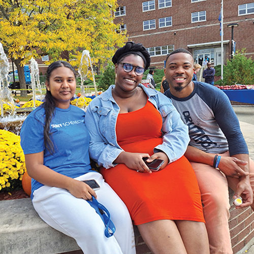 Three students sitting by the fountain in the Quad.