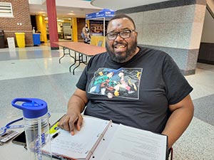 Adult student sitting at a table with a notebook open in front.