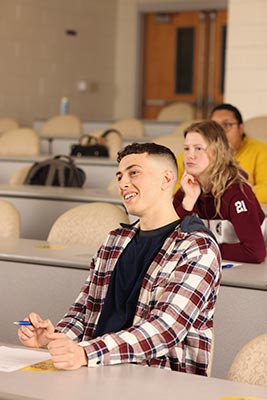 Students, socially, distanced, in a lecture hall. 