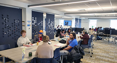 Students working with tutors at tables in the Learning Center. 