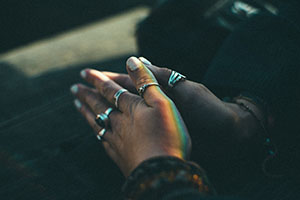 Hands held together in prayer, with light from a stained glass window shining down.