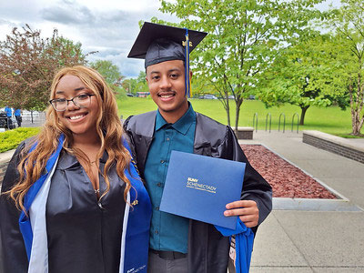 Two students in graduation robes after the ceremony. 