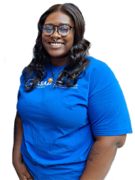 Female with black hair, glasses, and a nose ring, wearing a blue SUNY Schenectady shirt. 