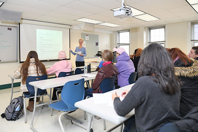 Hospitality students in a classroom setting, with Professor Ingrid O'Connell at the whiteboard.