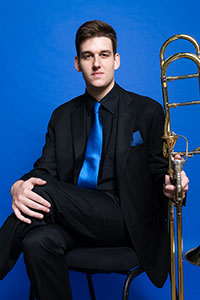 Dr. Stephen Whimple, seated, holding a trombone.