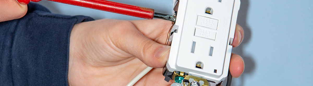 Close up shot of someone holding the pieces of an electrical outlet. 