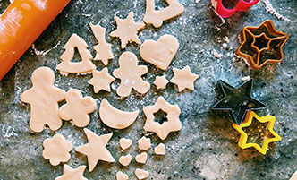 Raw cookie dough, cut into shapes, with cookie cutters off to the side. 