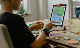 Young boy working on a coding project using a tablet. 