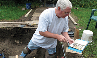 Man standing in a pit at an archaeology dig site. 