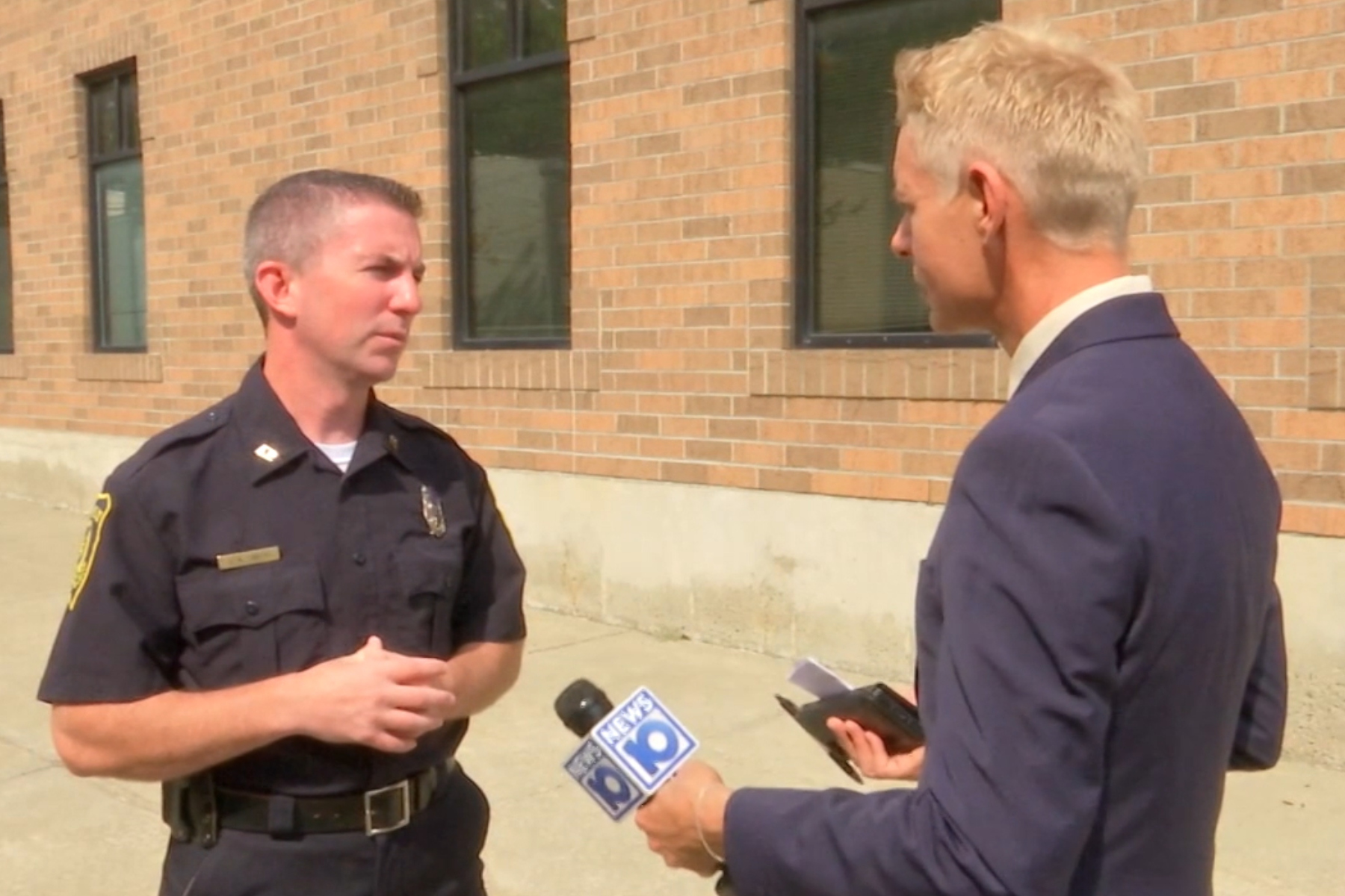 James De La Fuente holding NEWS10 microphone, conducting interview with police officer