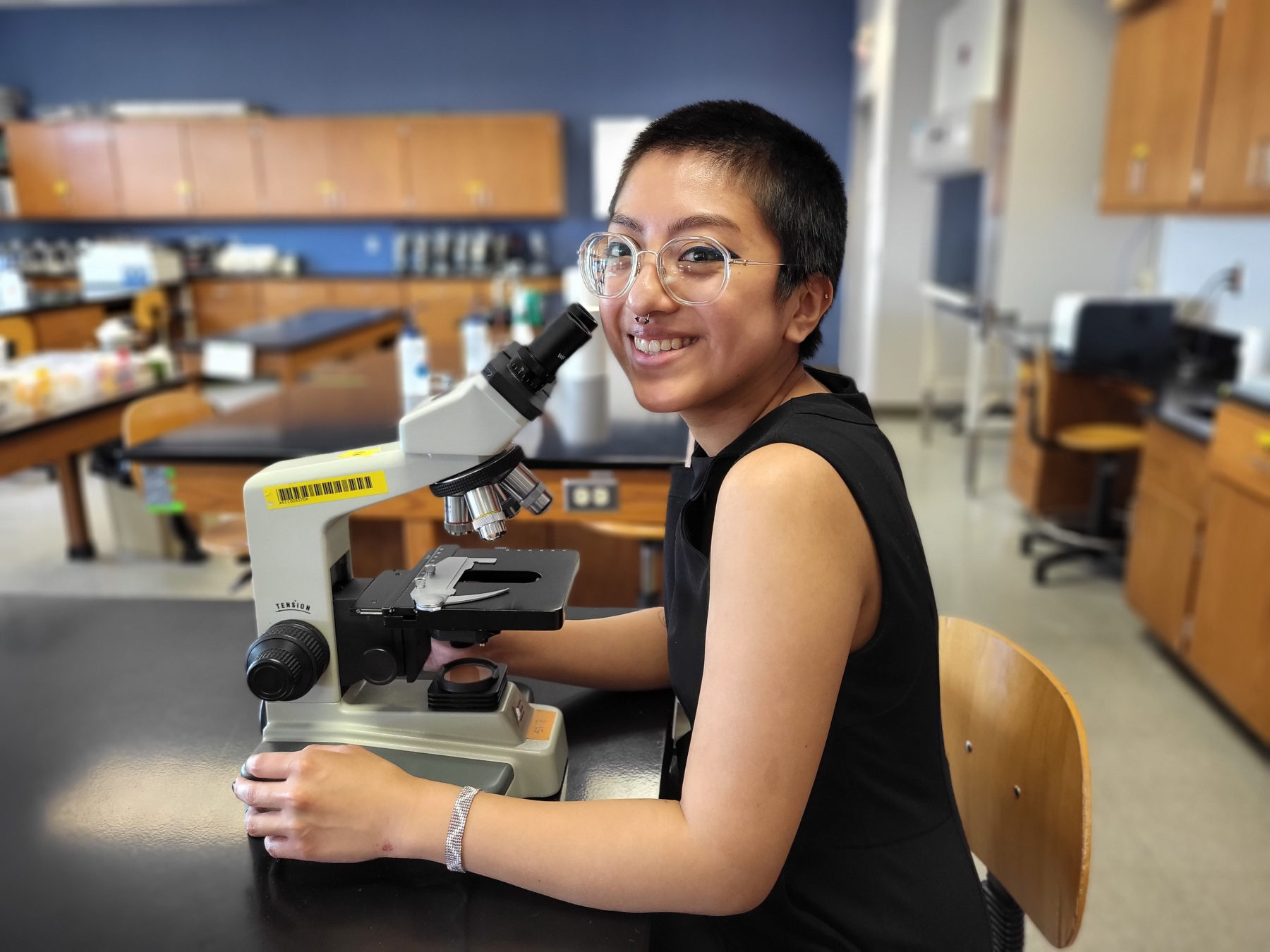 Jennifer Diaz sitting at a microscope in the Bio Lab.