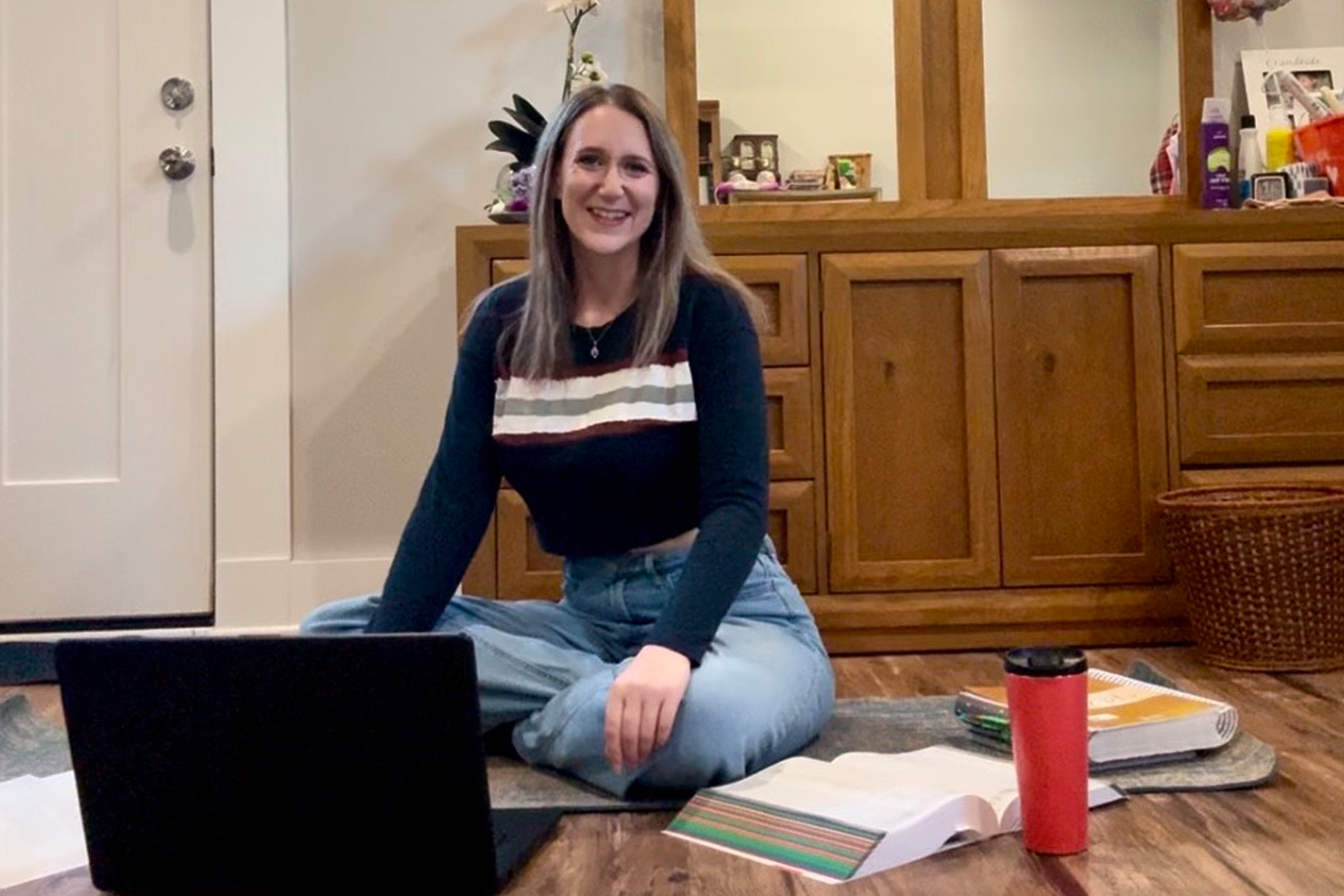 Meghan Conley, sitting on the floor in front of her laptop and books