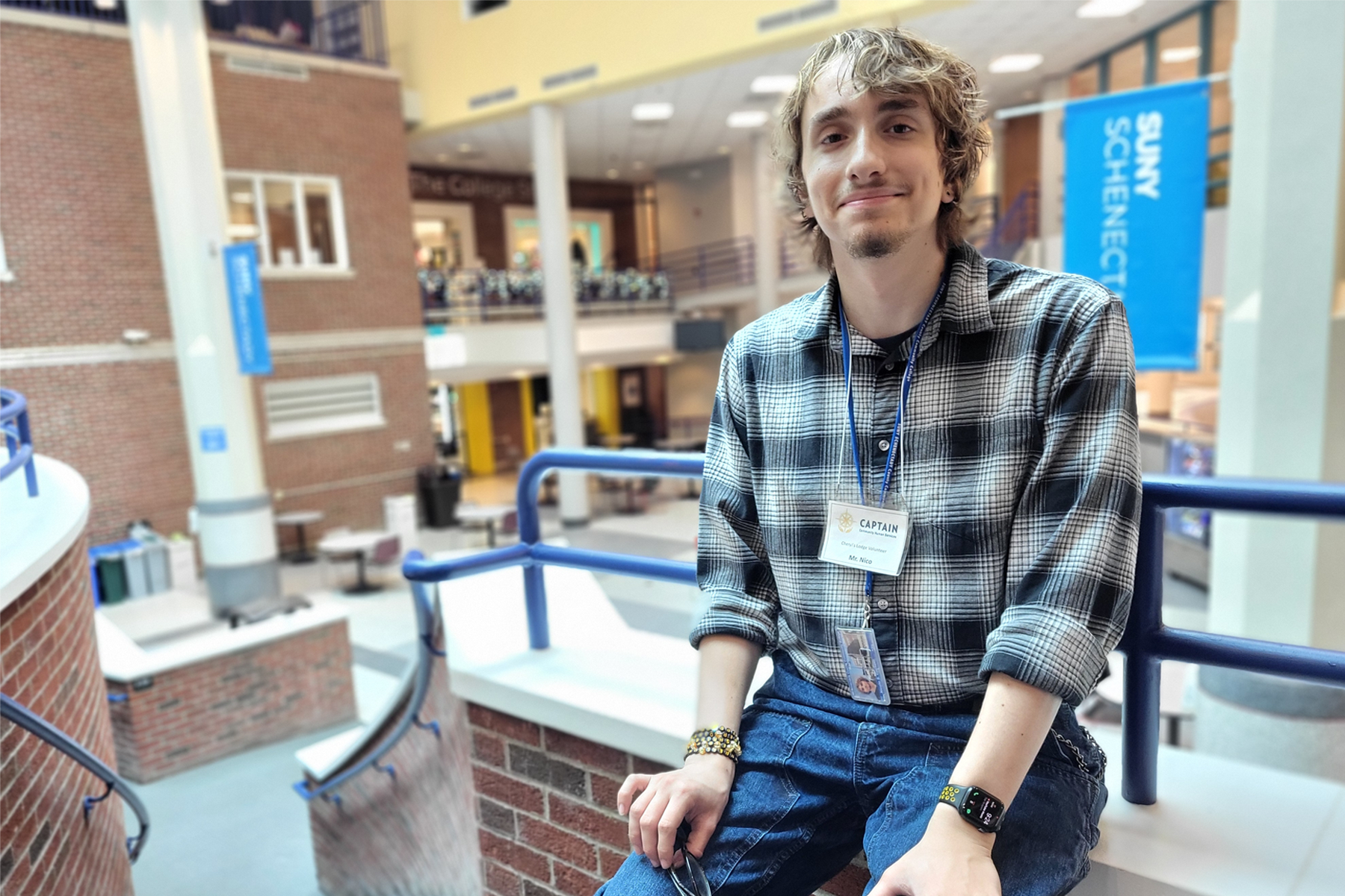 Nico Cochetti sitting down in Elston Hall with College banners behind him.