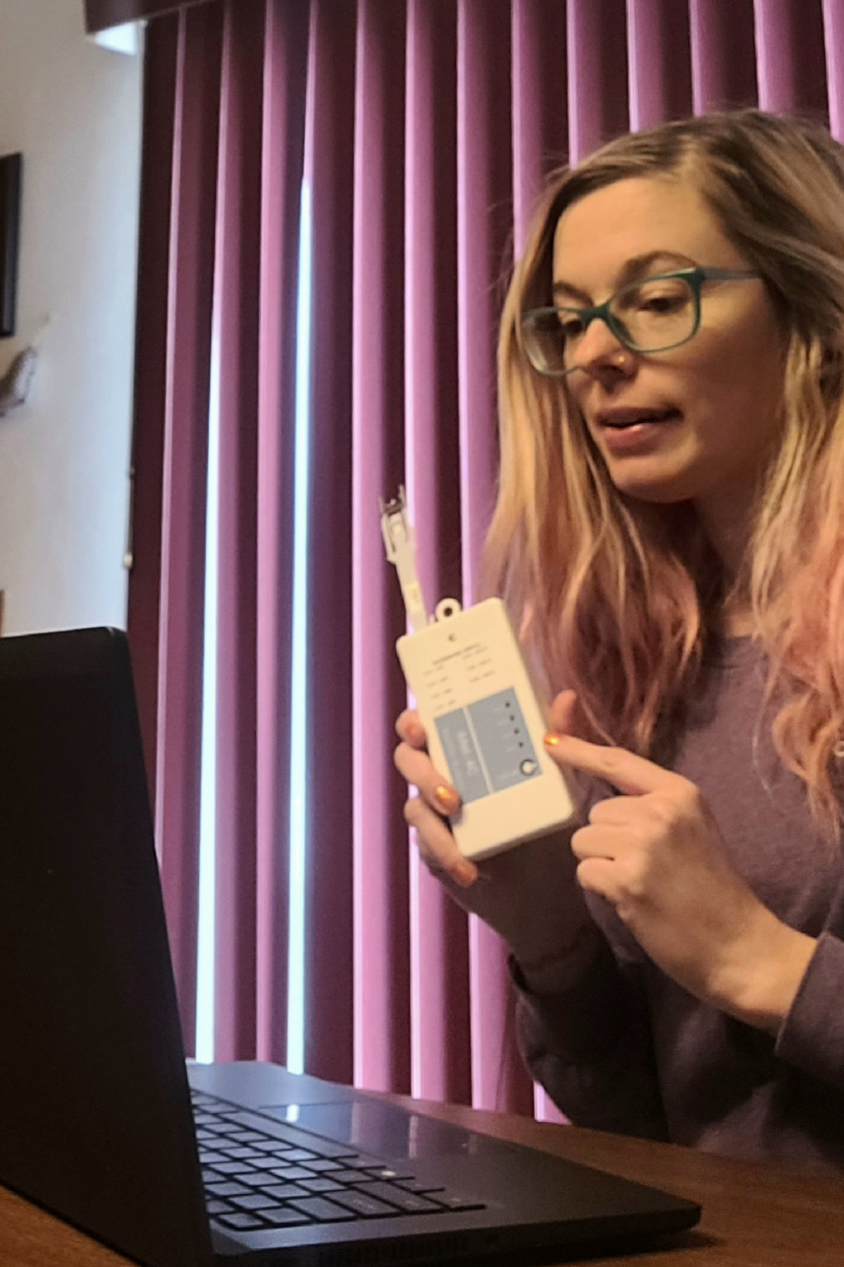 Erin Potter teaching facing laptop, teaching her online class, holding the instrument that goes with the weather ballon